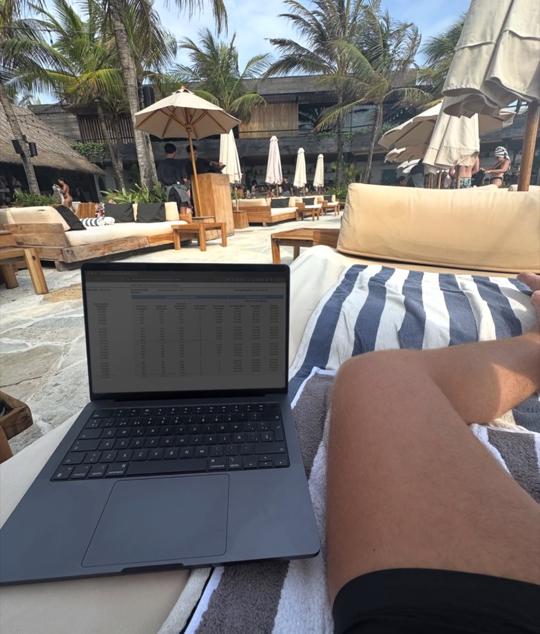 Agent working remotely from a tropical resort — laptop open on a beachside lounger